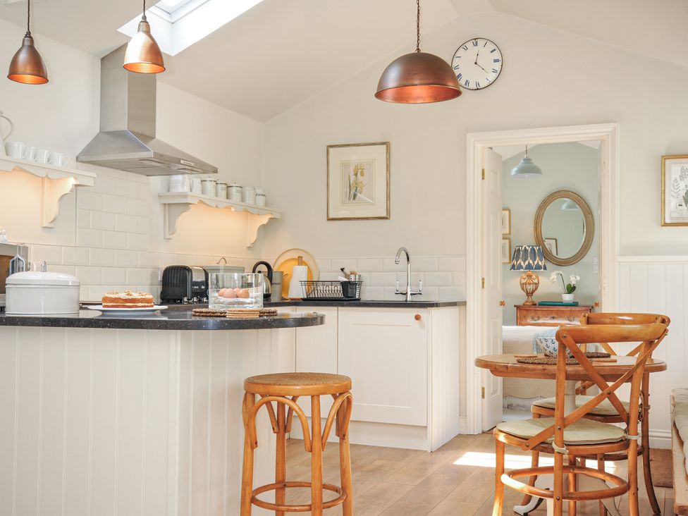 A kitchen with a stove and table at The Coach House at Pendower House in Fowey