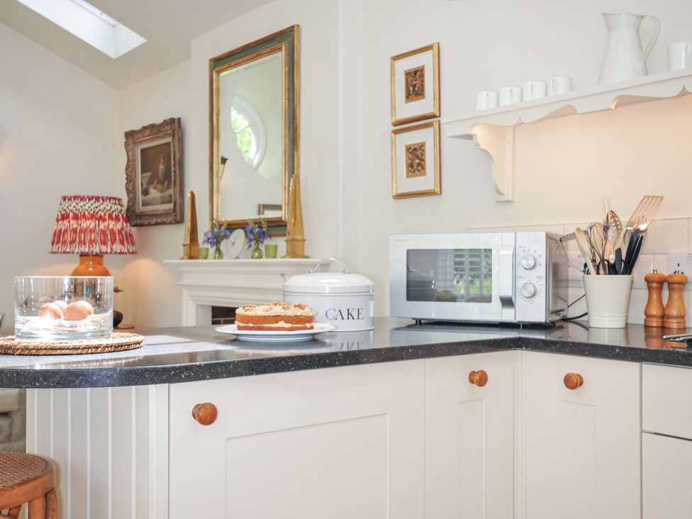A kitchen with a microwave and cake on the counter at The Coach House at Pendower House Fowey