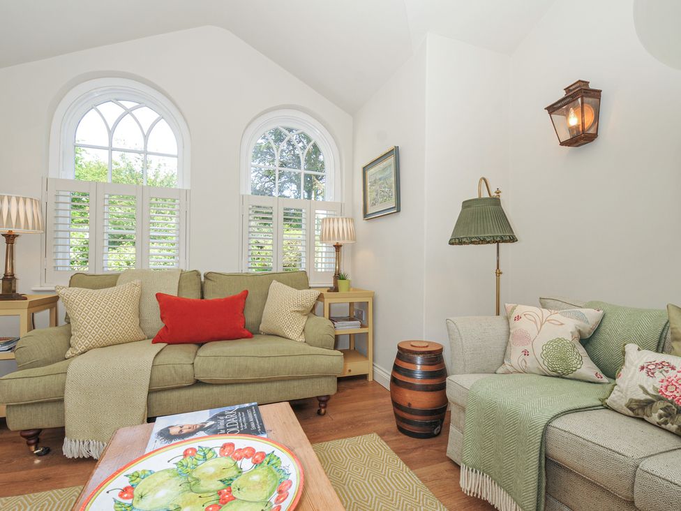 A living room with a green sofa and coffee table at The Coach House at Pendower House Fowey