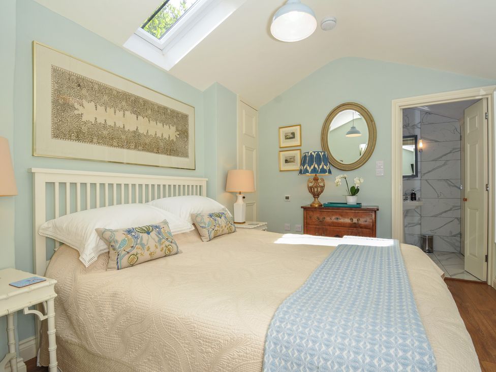 A bedroom featuring a bed with pillows and bedside table at The Coach House at Pendower House Fowey