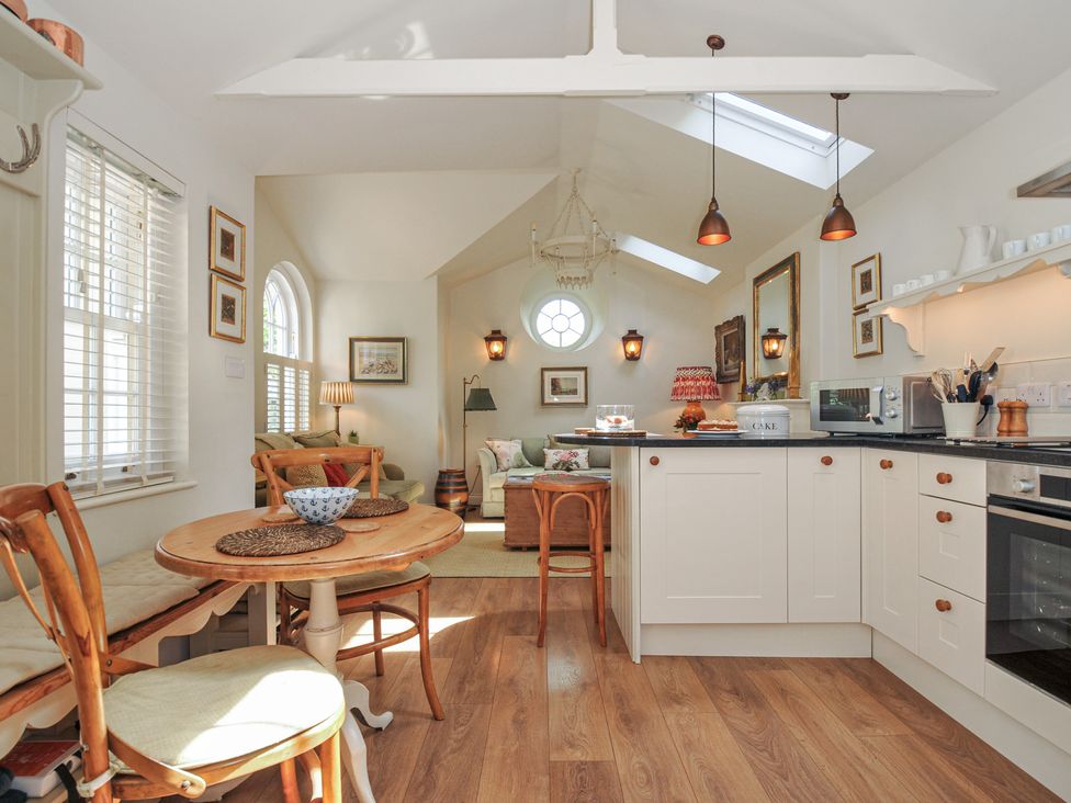 A kitchen with appliances and seating area at The Coach House at Pendower House Fowey