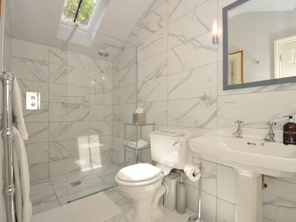 A bathroom with a shower, toilet, and sink at The Coach House at Pendower House in Fowey