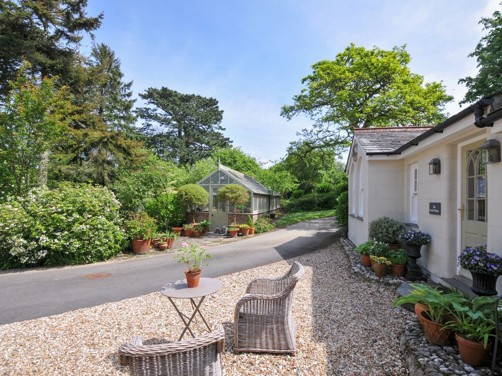 An outdoor area with a gravel path and a greenhouse at The Coach House at Pendower House, Fowey