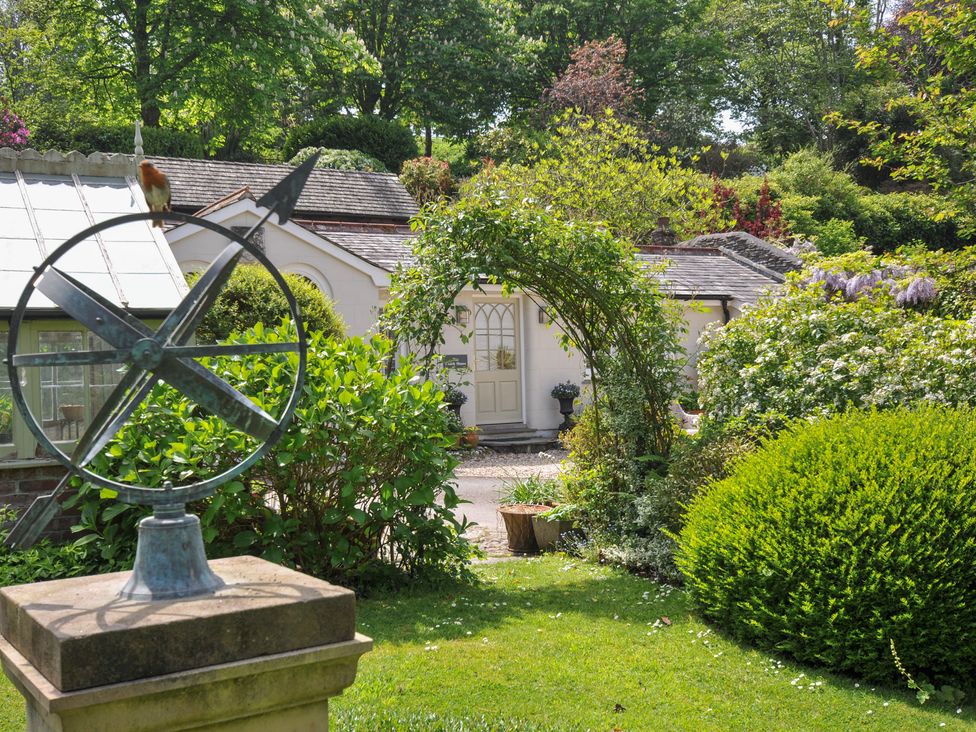 A garden with a compass and ornamental arch at The Coach House at Pendower House in Fowey