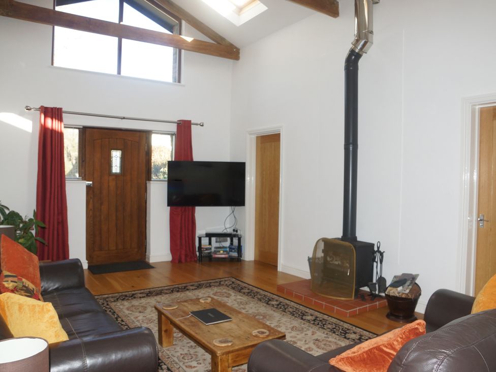 A living room with a wood stove and TV at Dilly Dally Barn near Bude