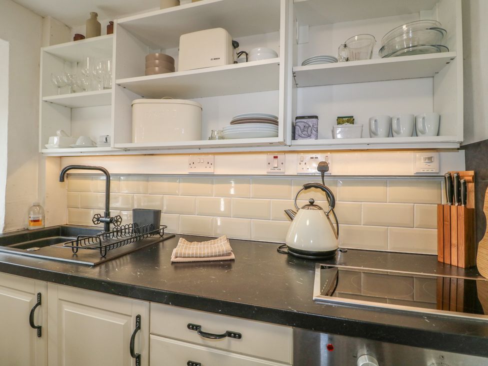 A kitchen countertop with a kettle, sink, and dish rack at The Hill in Cromford