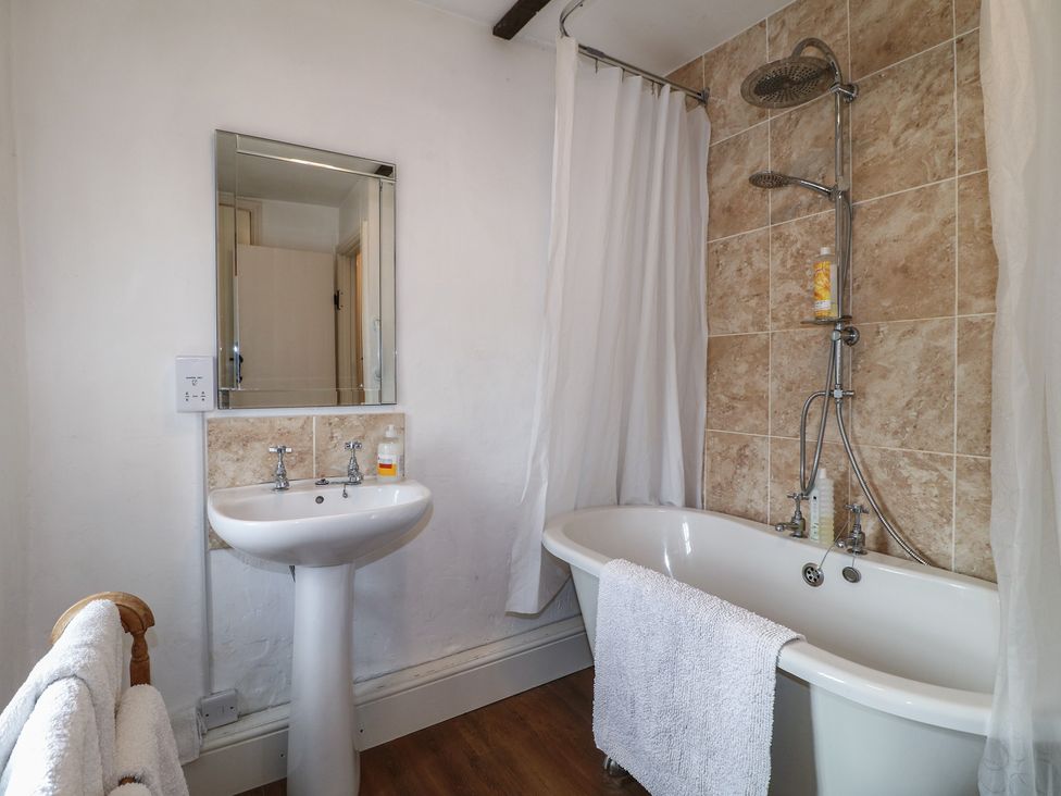 A bathroom with a bathtub, shower, sink, and mirror at The Hill in Cromford