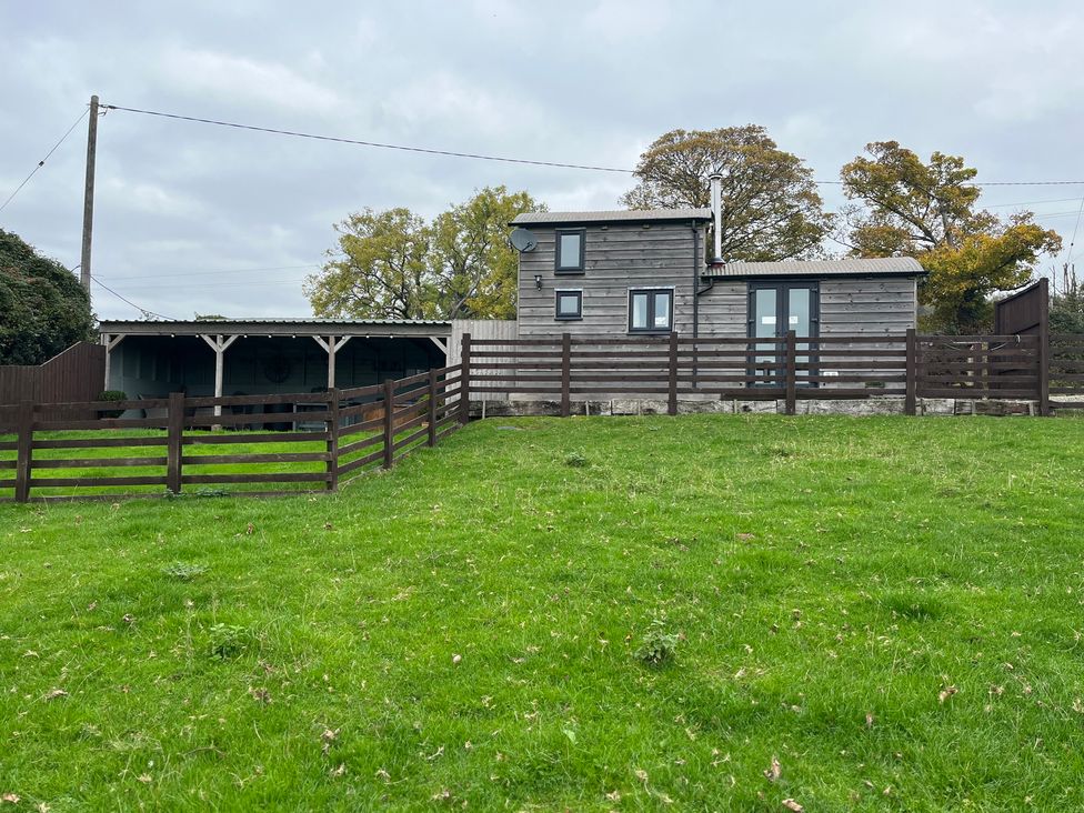A house with a fence and grass at Shepherds Cabin at Titterstone Clee Hill