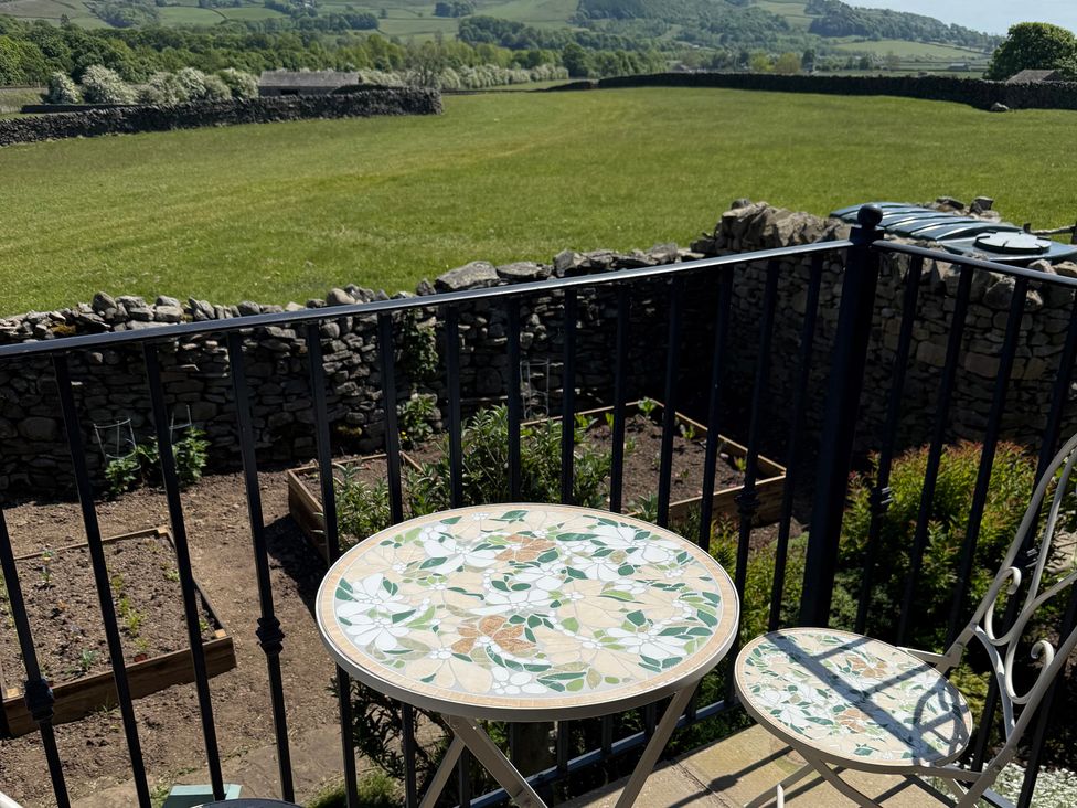 A table and chair with a view of a garden and field at Melsome Barn Giggleswick near Settle