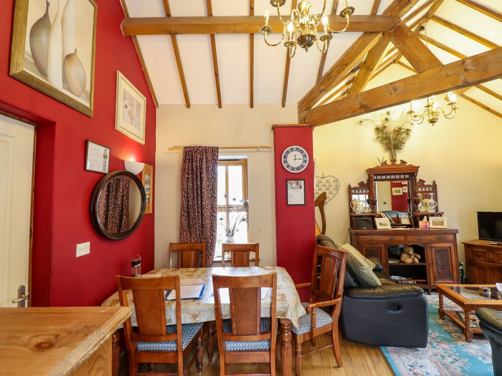 A dining room with a wooden table and chairs at Gelli Glud in Eglwysbach