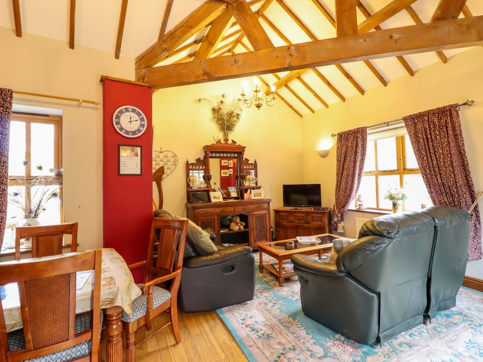 A living room with a sofa and dining table at Gelli Glud in Eglwysbach