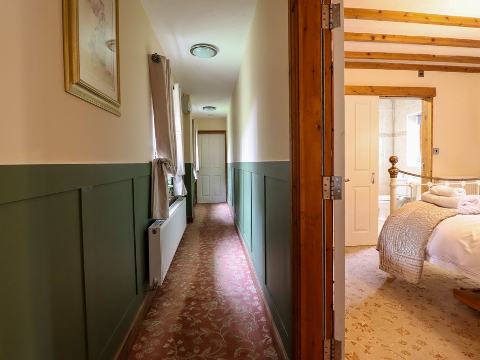 A hallway with a radiator and an open bedroom door at Gelli Glud in Eglwysbach