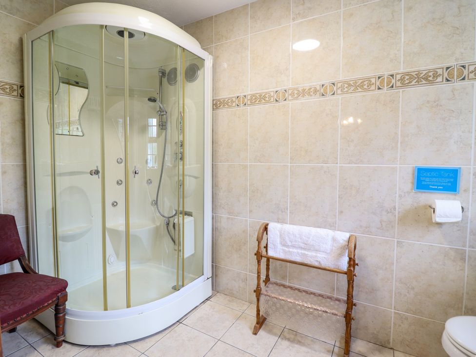 A bathroom with a shower, toilet, and towel rack at Gelli Glud in Eglwysbach