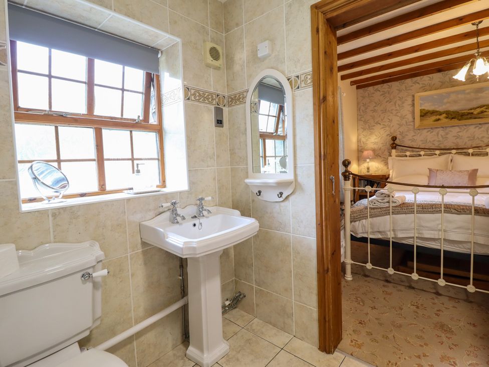 A bathroom with a sink and toilet looking into a bedroom at Gelli Glud in Eglwysbach