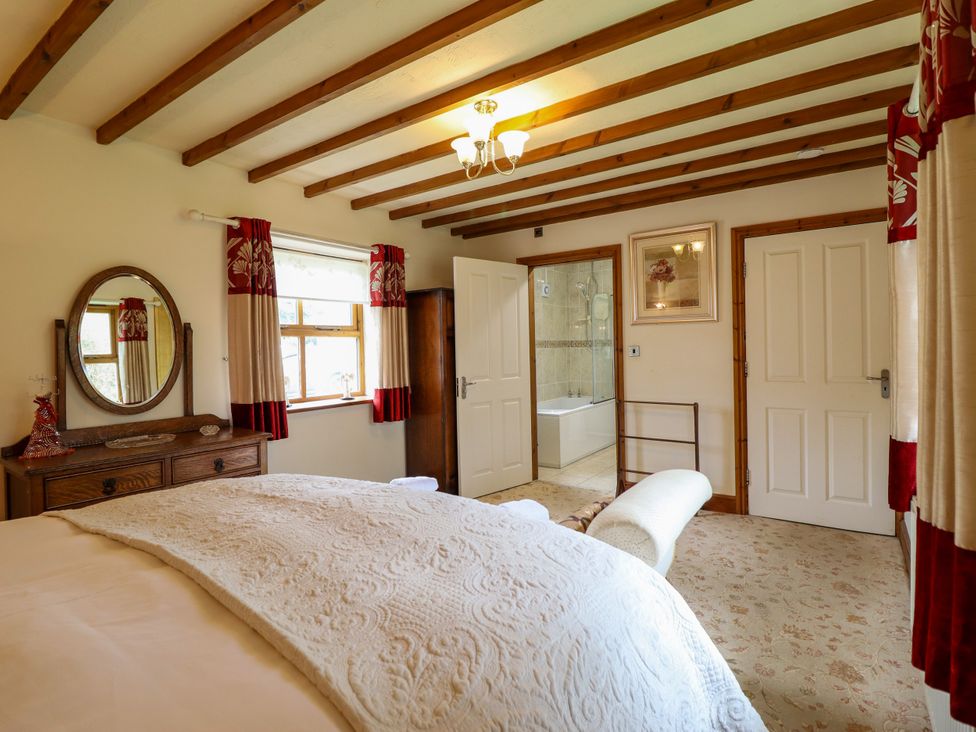 A bedroom with a bed and a mirror at Gelli Glud in Eglwysbach