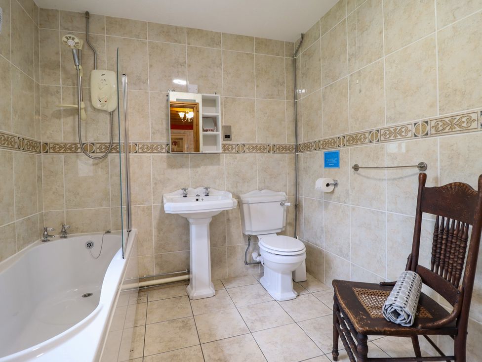 A bathroom with a bathtub, shower, sink, and toilet at Gelli Glud in Eglwysbach