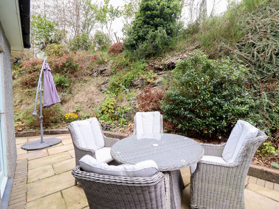 A table with chairs and an umbrella stand in an outdoor area at Gelli Glud in Eglwysbach