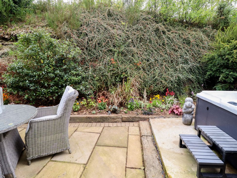 A garden with a table and chairs alongside a hot tub at Gelli Glud in Eglwysbach