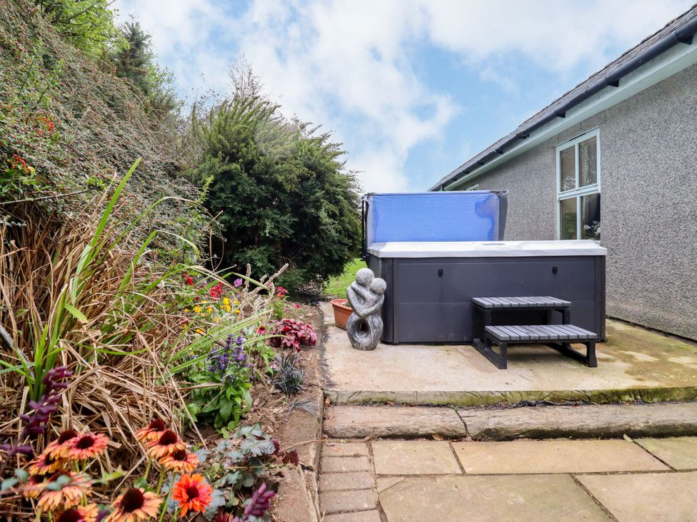 A garden with a hot tub and flowers at Gelli Glud in Eglwysbach