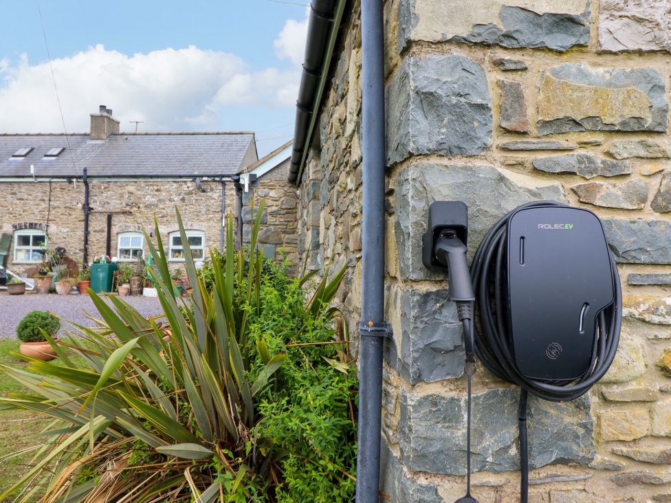 An electric vehicle charger mounted on a stone wall at Gelli Glud Eglwysbach