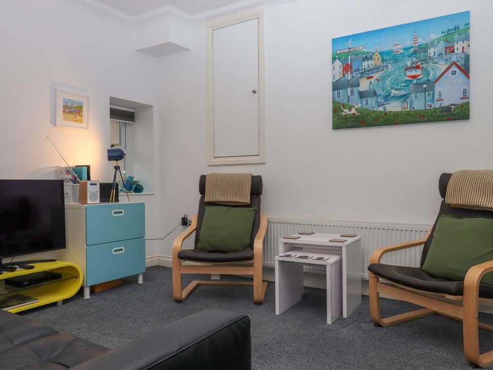 A living room with a television and armchairs at Cottage 1 Newcourt Torquay