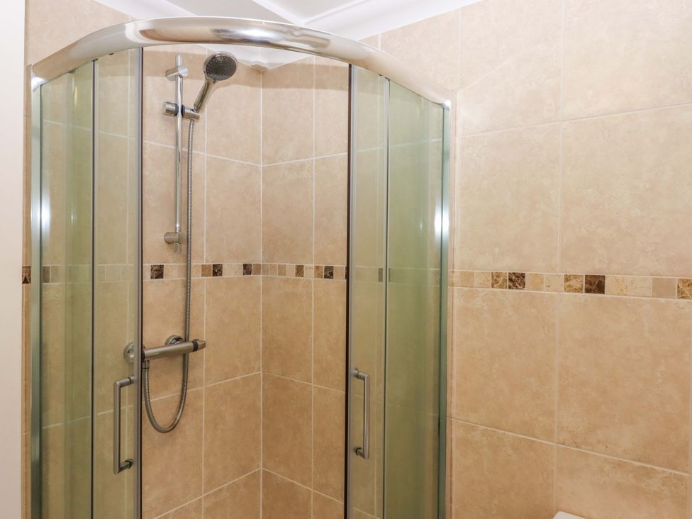 A shower area with glass door and tiled walls at Cottage 1 Newcourt Torquay