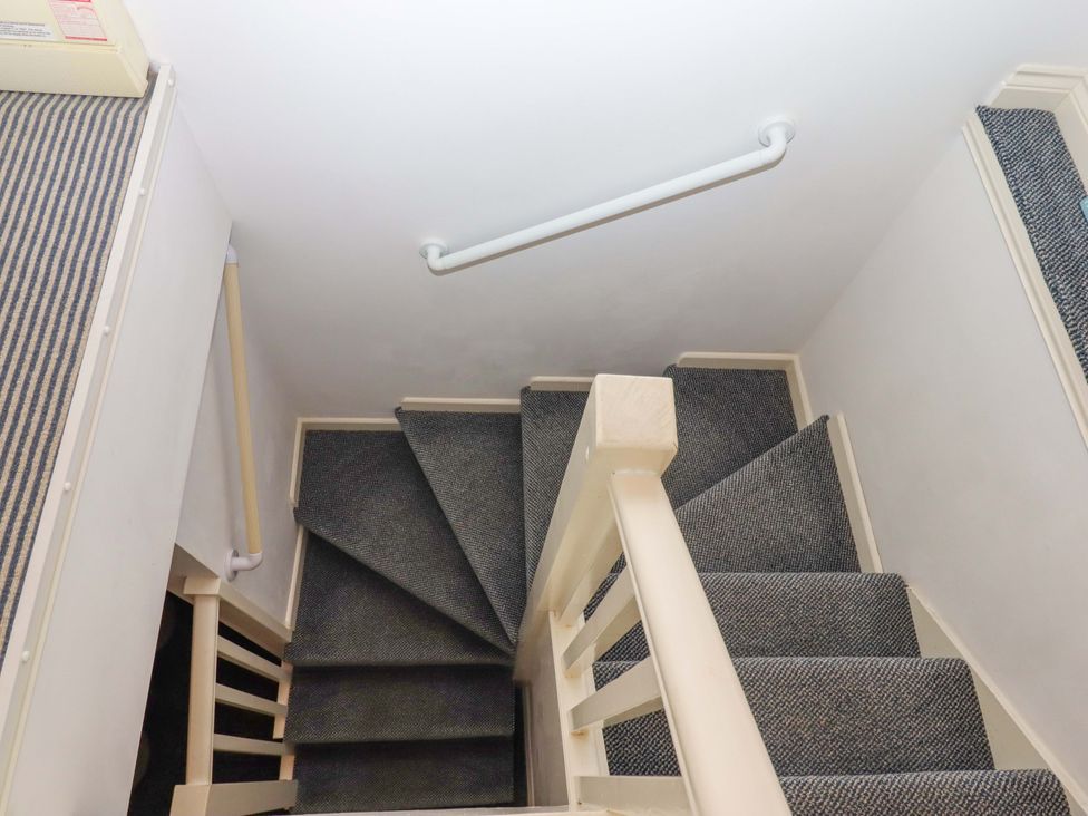 A staircase with carpet and a handrail at Cottage 1 Newcourt in Torquay