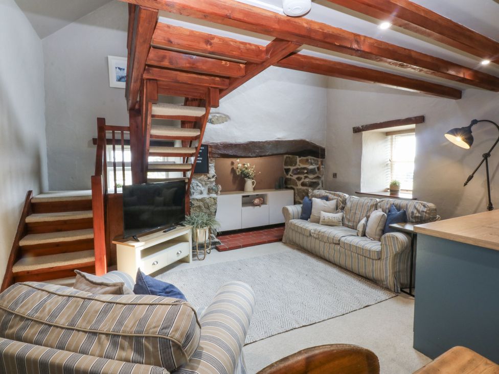 A living room with a staircase and television at Cegin Foch in Chwilog