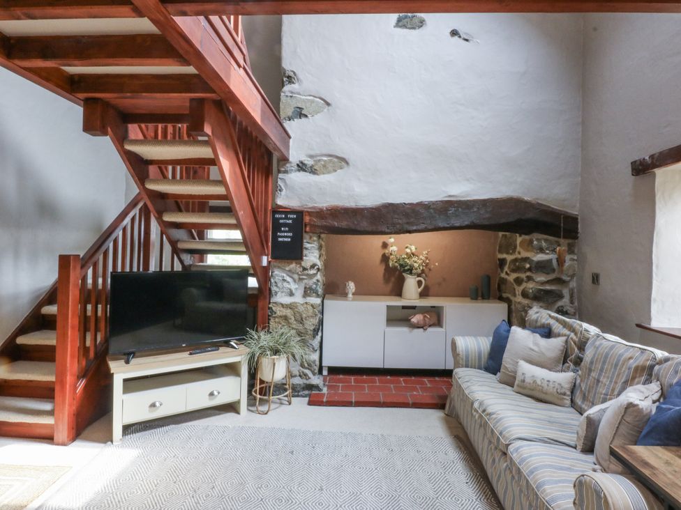 A living room with a staircase and a television at Cegin Foch in Chwilog
