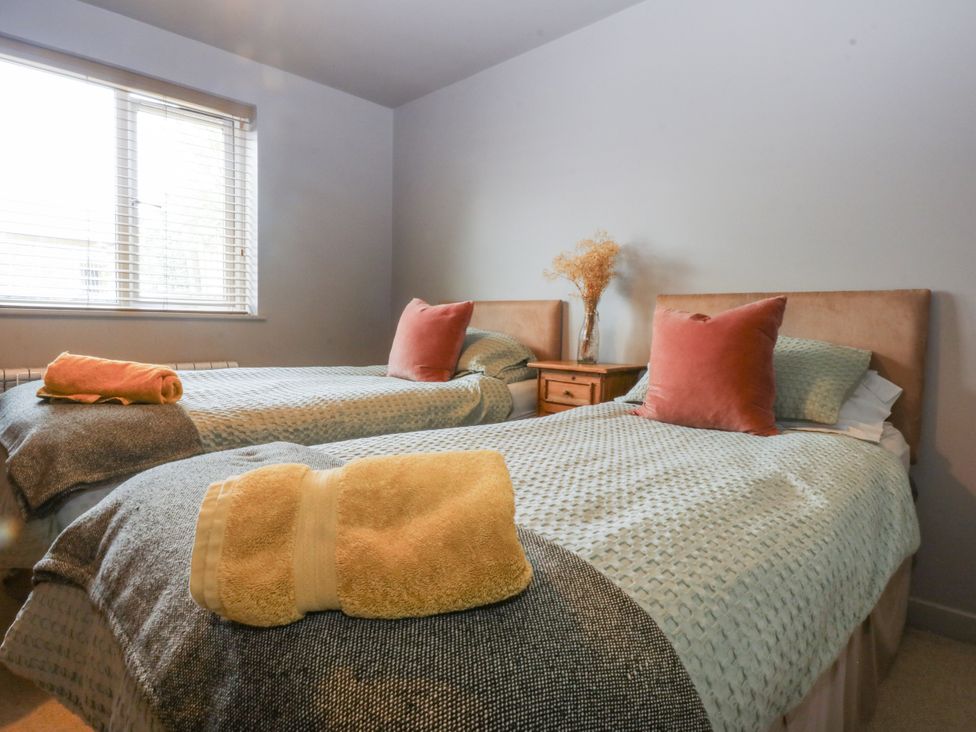 A bedroom with two beds and a nightstand at Cegin Foch in Chwilog