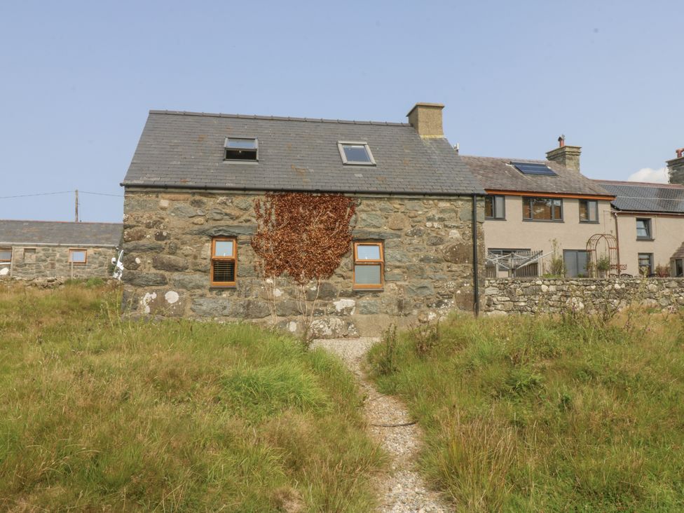 An exterior view of a stone house with a gravel path at Cegin Foch in Chwilog