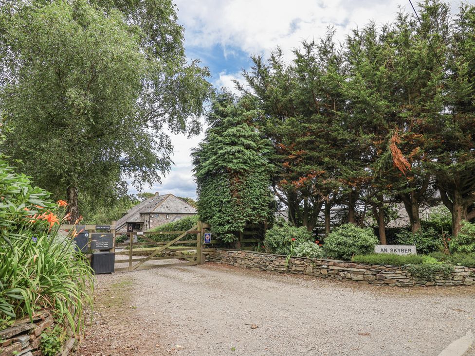 A gravel path leading to a gate with trees and a sign for An Skyber in Tideford