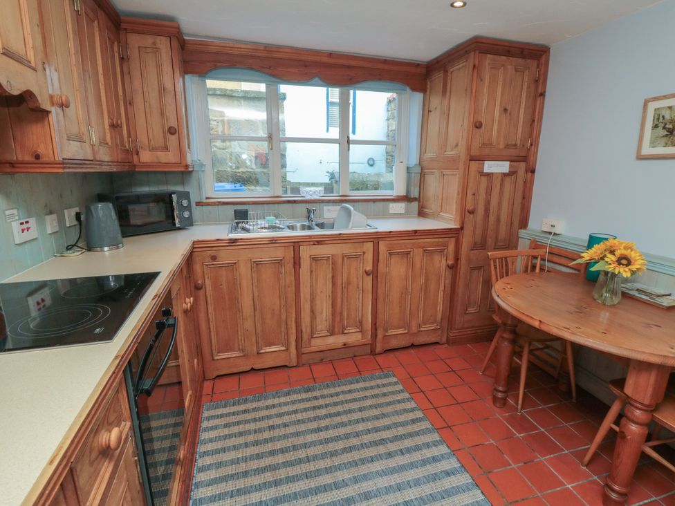 A kitchen with wooden cabinets and a table at Bramla in Staithes