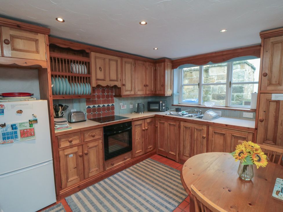 A kitchen with wooden cabinets and appliances at Bramla in Staithes