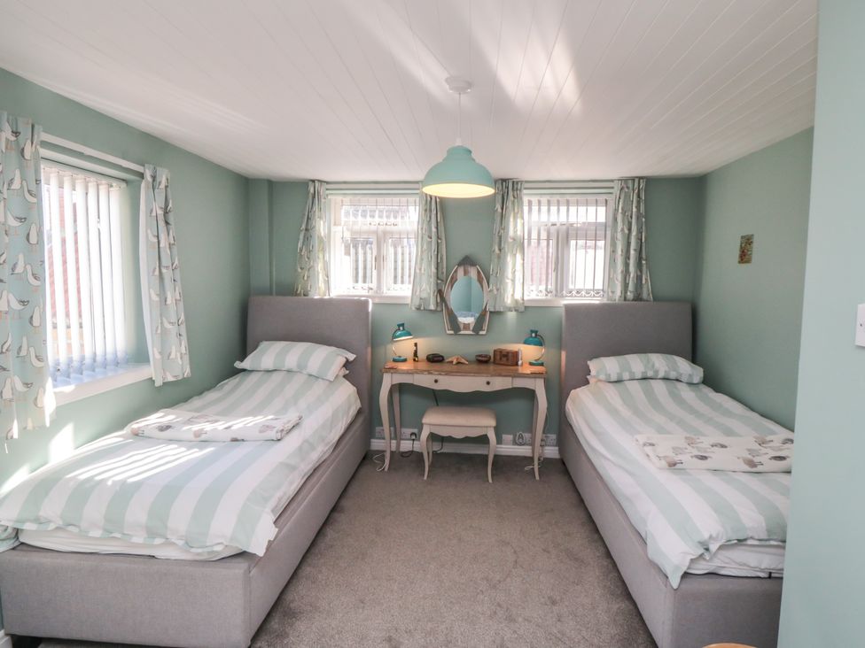 A bedroom with two single beds and a desk at Bramla in Staithes