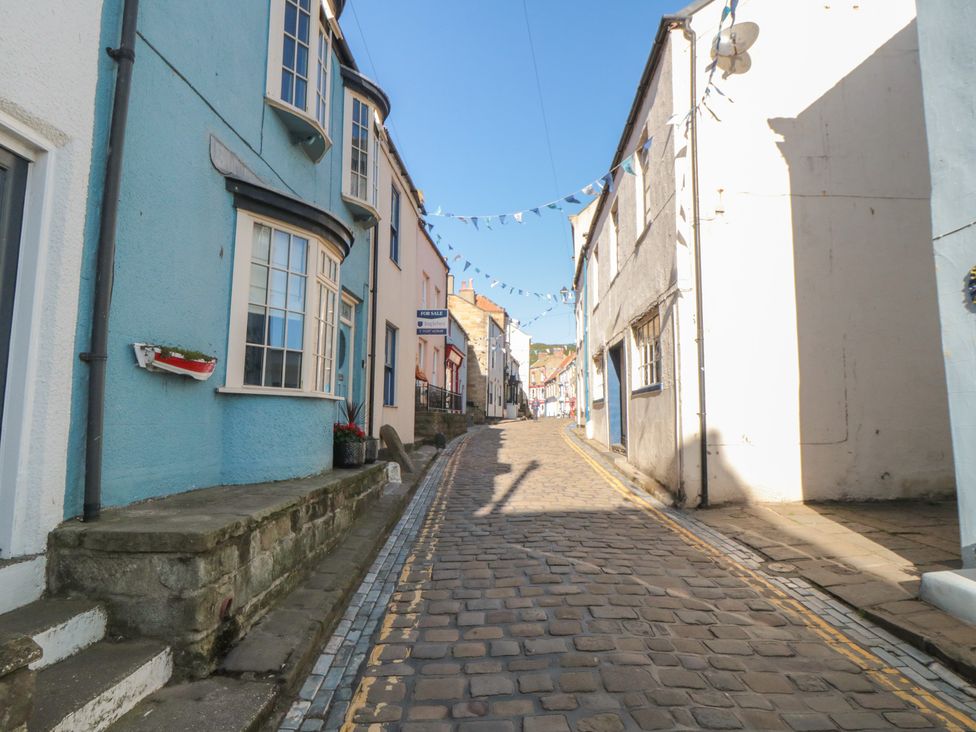 A cobblestone street with blue and white houses at Bramla in Staithes