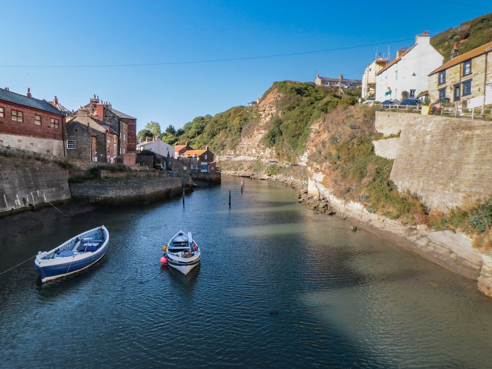 A river with boats and buildings along the shore at Bramla in Staithes