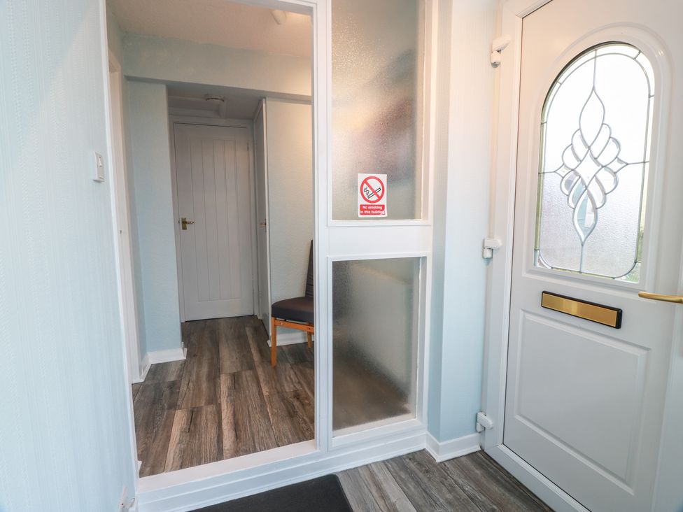 A hallway with an entrance door and chair at Mardan in Southerness