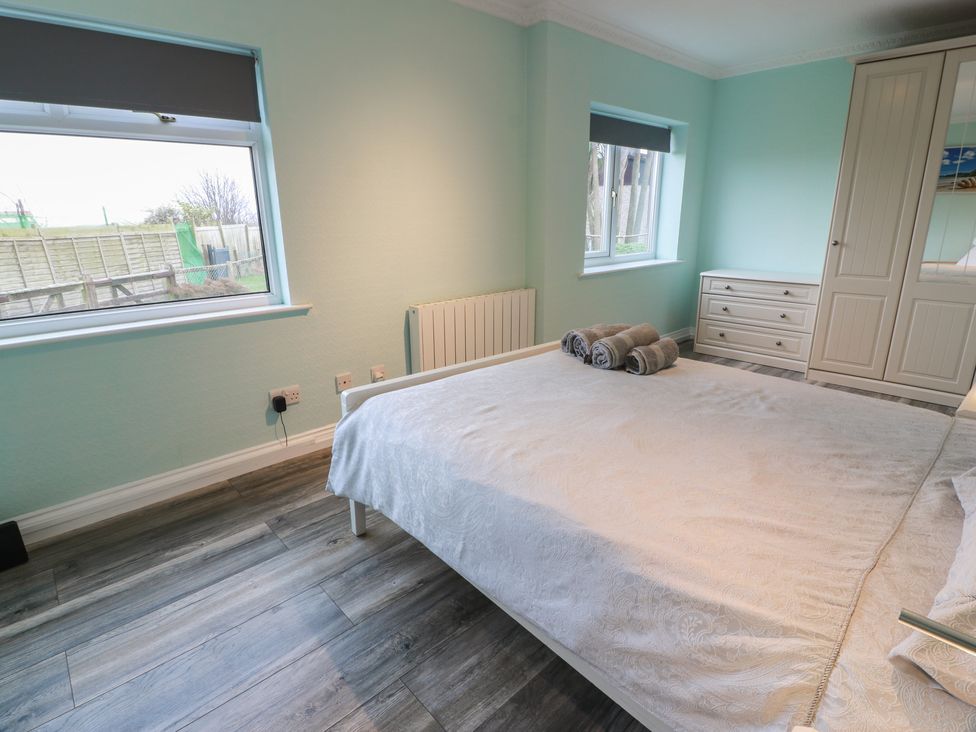 A bedroom with a bed, wardrobe and windows at Mardan in Southerness