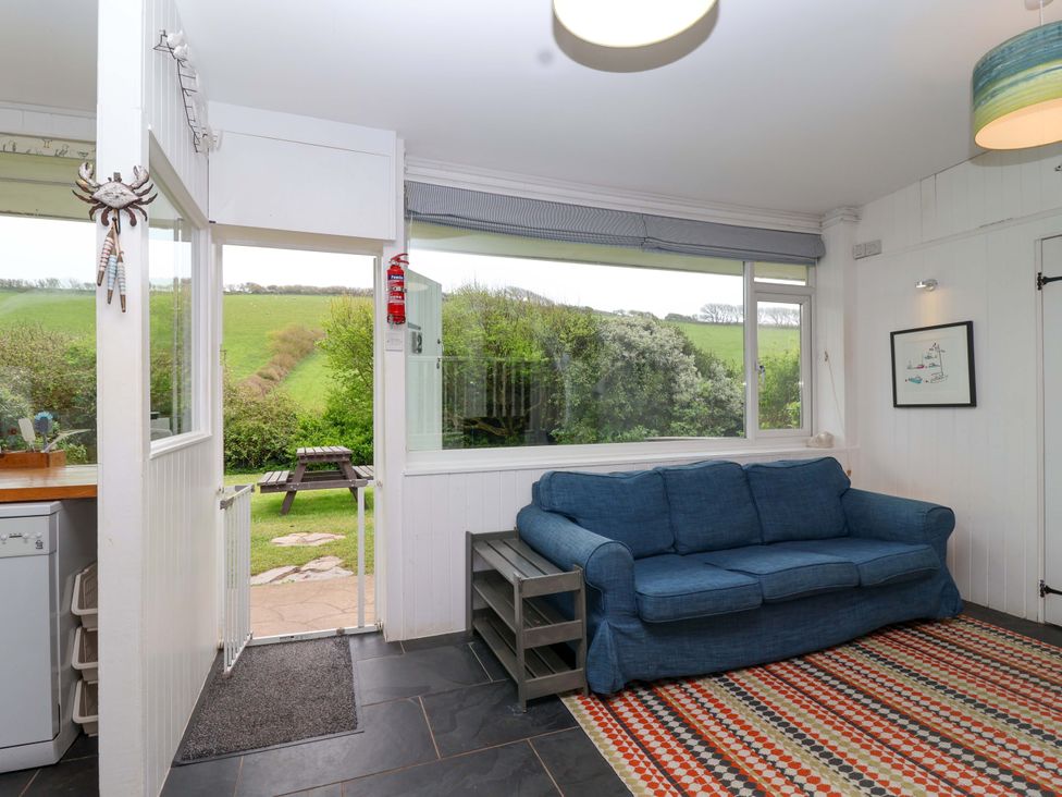 A snug with a sofa and door leading outside at 2 Brook Cottages in Hope Cove