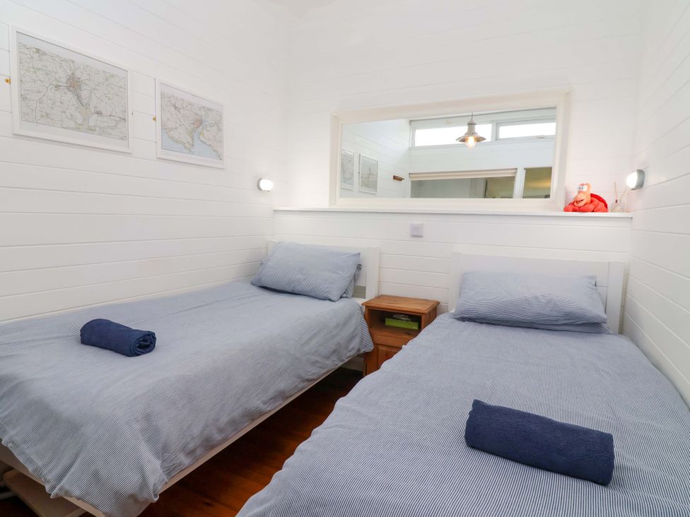 A bedroom with two beds and a bedside table at 2 Brook Cottages in Hope Cove