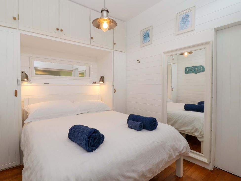 A bedroom with a bed and towels at 2 Brook Cottages in Hope Cove
