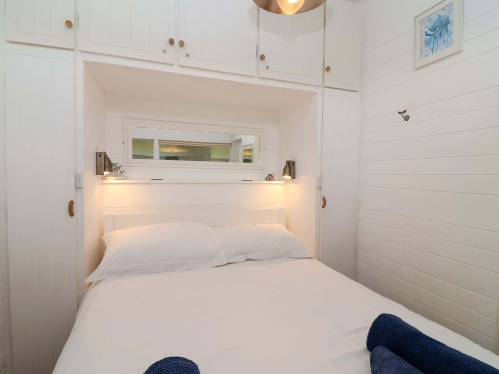 A bedroom with a bed and wardrobe at 2 Brook Cottages in Hope Cove