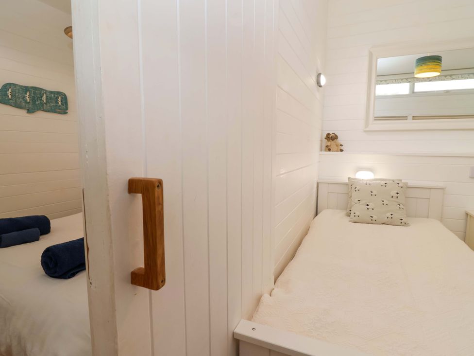 A twin bedroom with beds and a mirror at 2 Brook Cottages Hope Cove