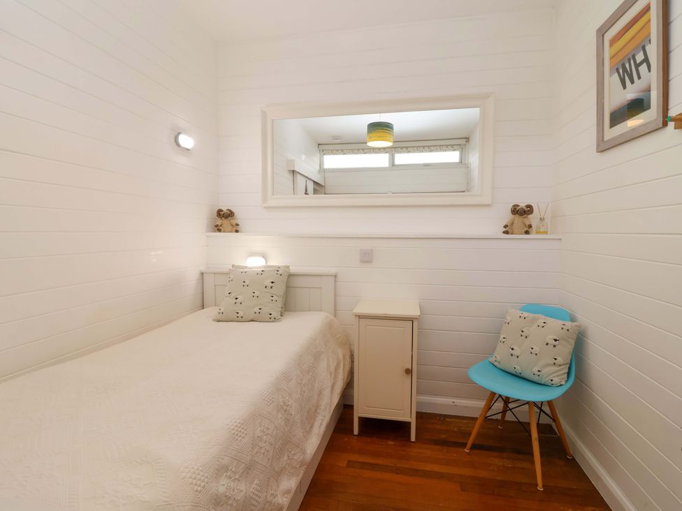 A bedroom with a bed, nightstand, and chair at 2 Brook Cottages, Hope Cove