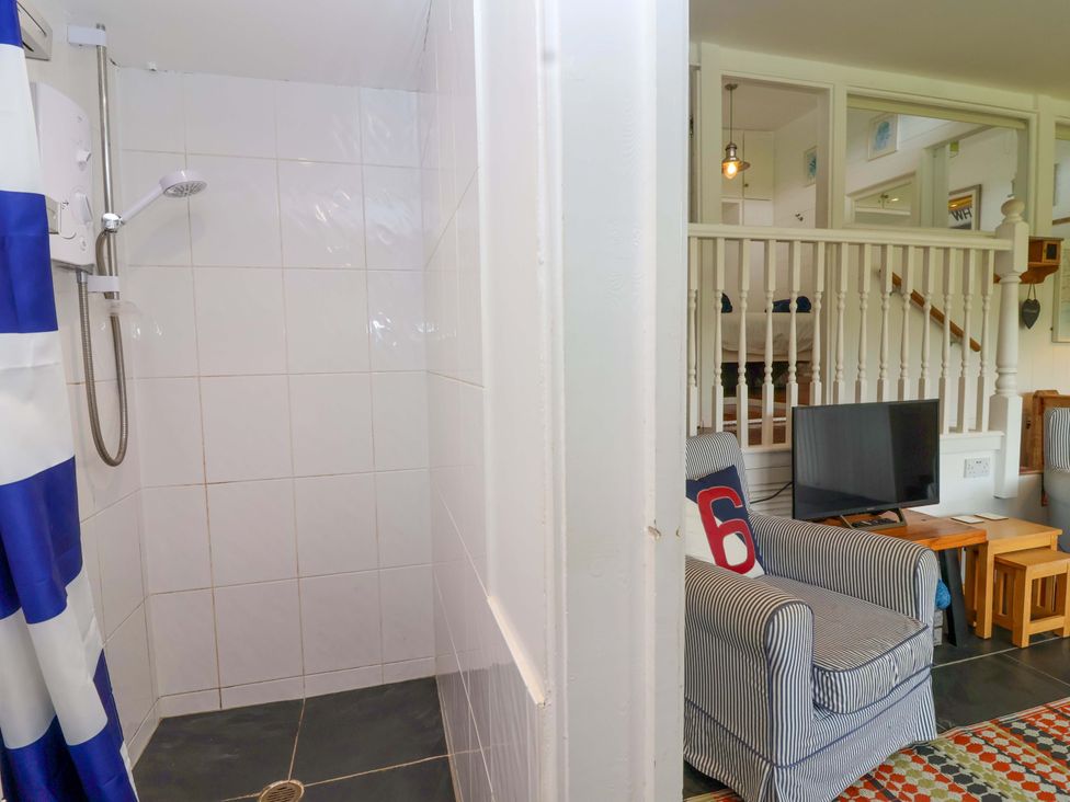 A bathroom with a shower and a seating area at 2 Brook Cottages, Hope Cove