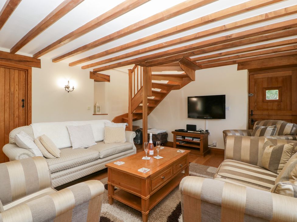 A living room with a coffee table and a staircase at Penrhiwarwydd Barn in Pontywaun