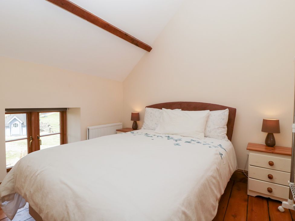 A bedroom with a bed and lamps at Penrhiwarwydd Barn in Pontywaun
