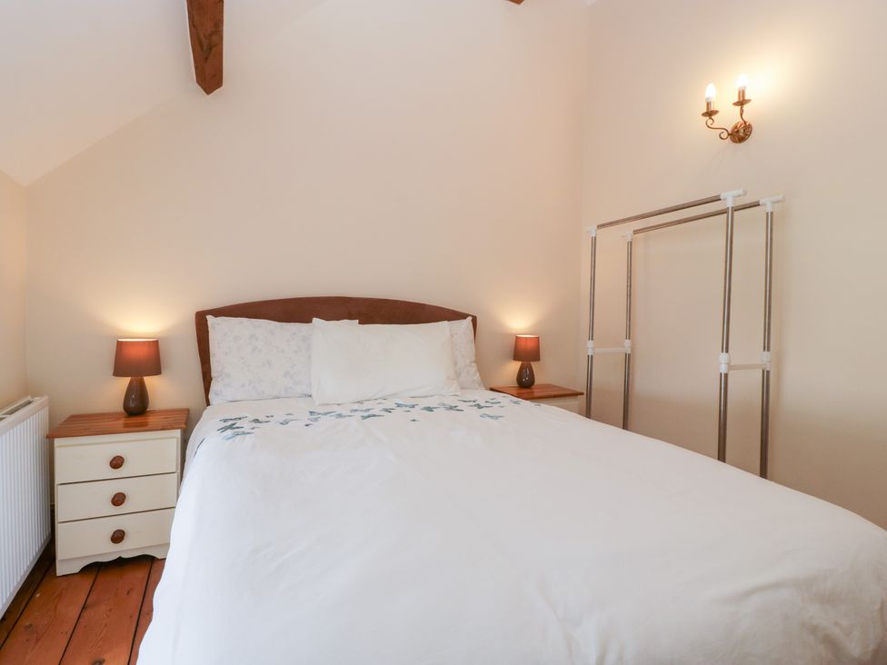 A bedroom with a bed and nightstand at Penrhiwarwydd Barn Pontywaun