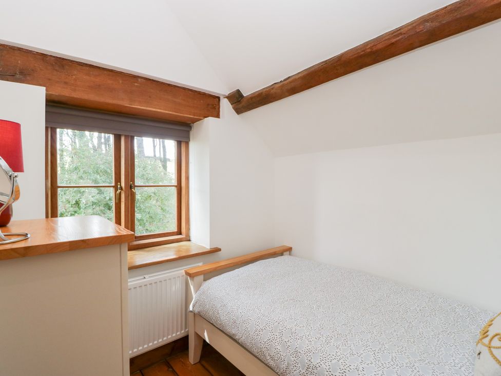 A bedroom with a bed and window at Penrhiwarwydd Barn Pontywaun
